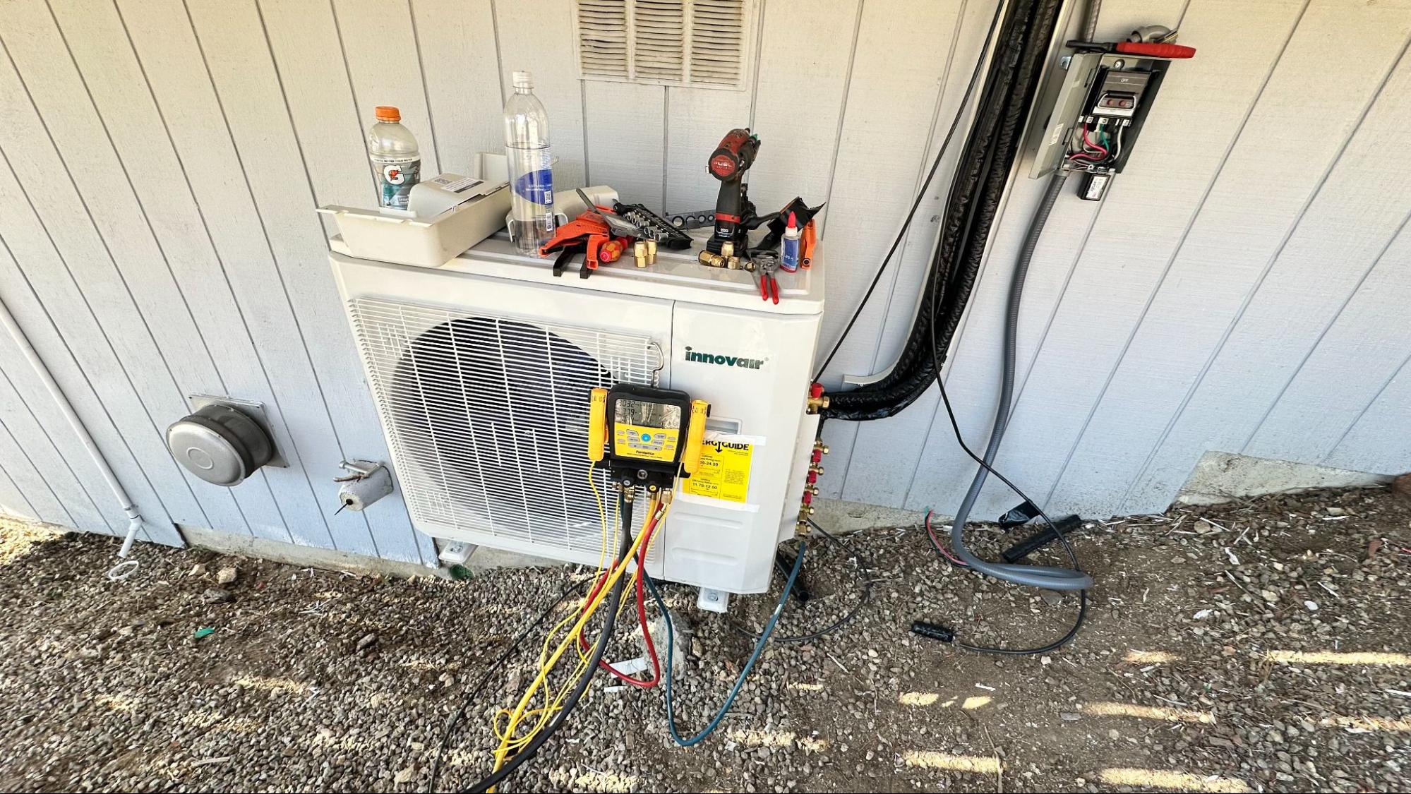 Technician performing maintenance checks on an outdoor HVAC condenser, part of routine heating and cooling upkeep in Tehachapi