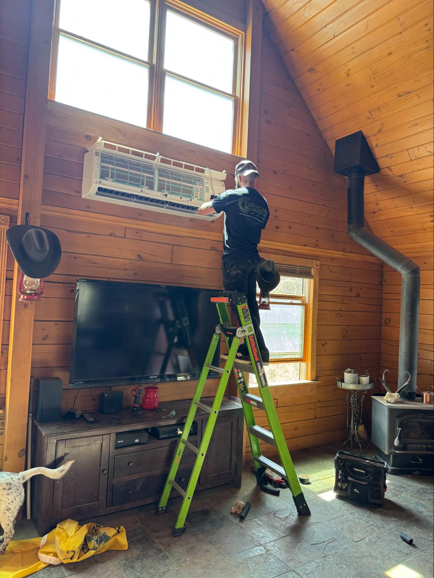 Technician installing a wall-mounted mini-split unit beneath a vaulted ceiling, reflecting how ceiling height influences cooling design