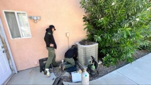 Origin Heating & Air technicians performing seasonal maintenance on a home's outdoor HVAC unit