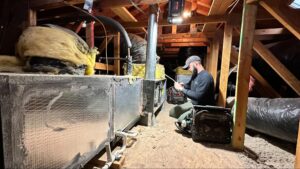 Technician repairing AC evaporator coil in attic in Palmdale, CA by Origin Heating & Air
