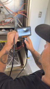 Technician using borescope camera to inspect furnace burner in Palmdale, CA by Origin Heating & Air