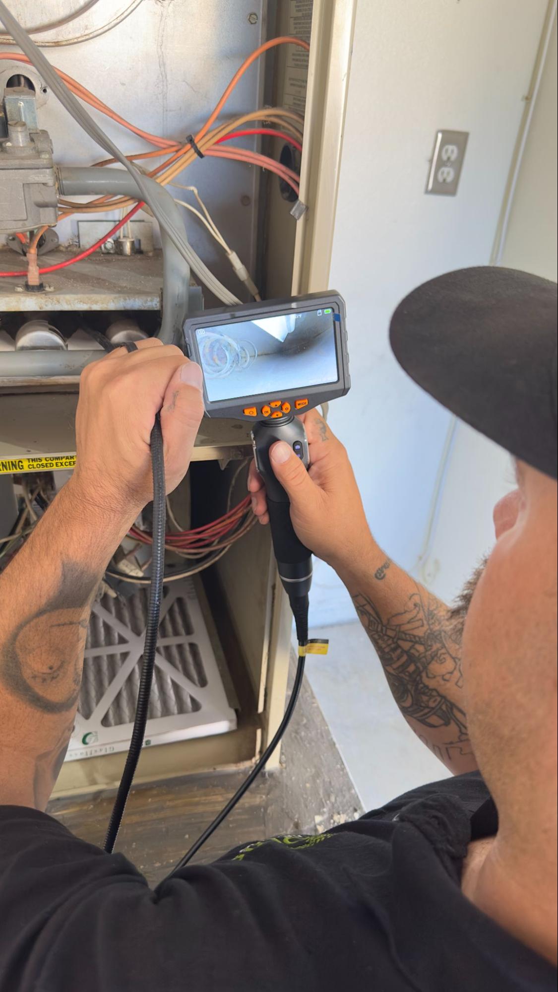 Technician using borescope camera to inspect furnace burner in Palmdale, CA by Origin Heating & Air