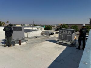 Origin Heating & Air technicians inspecting rooftop HVAC units as part of scheduled maintenance service