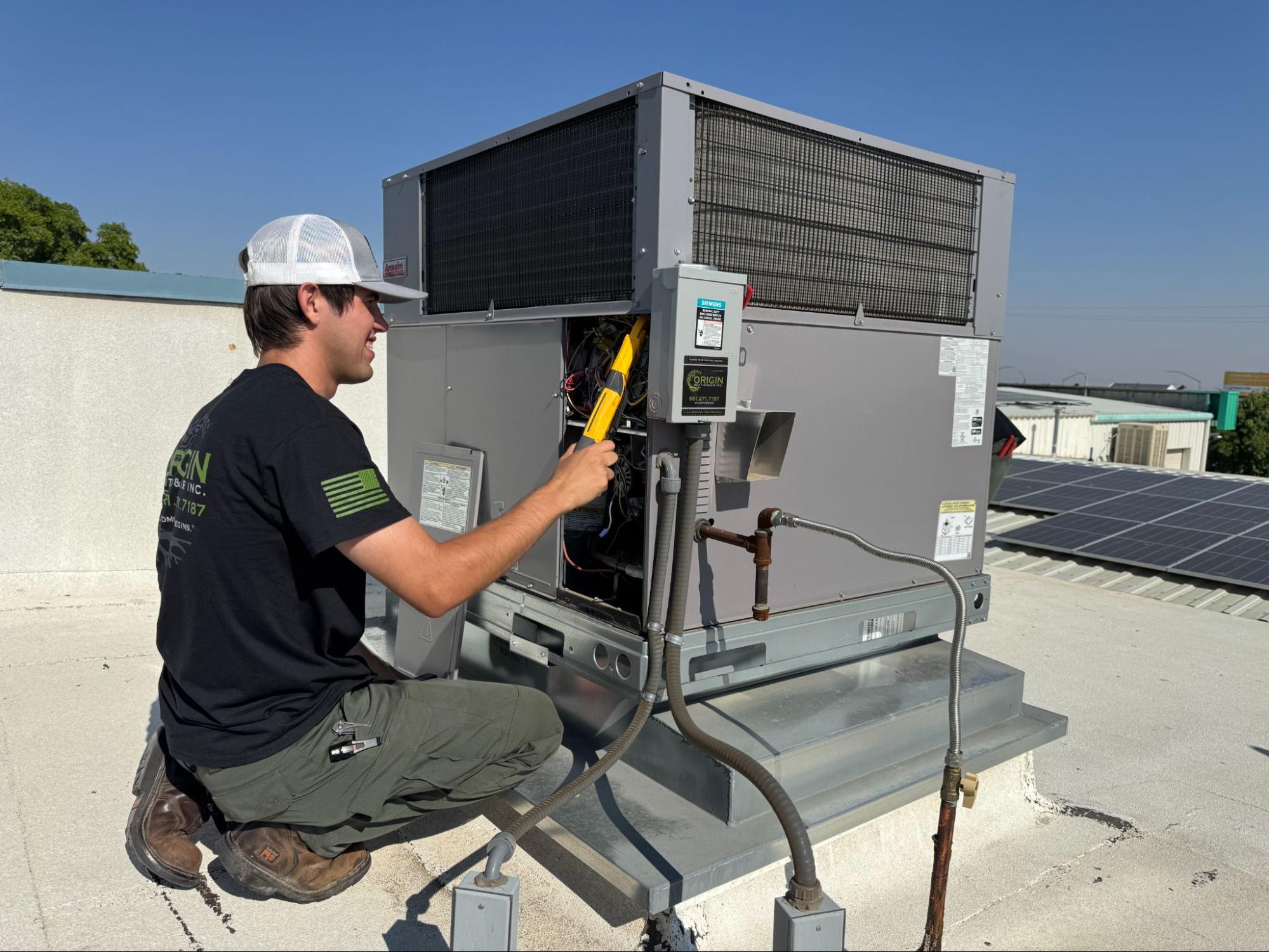 Technician performing AC repair on rooftop package unit in Palmdale, CA by Origin Heating & Air