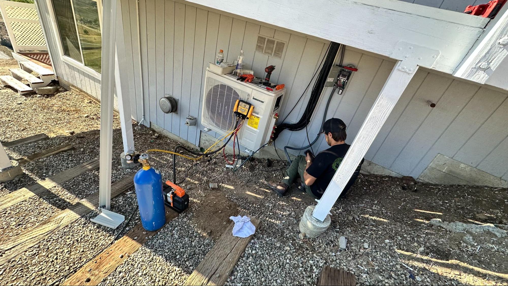 Technician servicing ductless mini split AC unit in Palmdale, CA by Origin Heating & Air